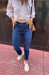 Pantalón de jean azul oscuro, corte recto, tiro alto y detalles de costuras en la parte superior.