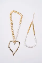 Set de dos collares plateados. Uno de ellos presenta una cadena de eslabones combinada con perlas irregulares y un dije grande en forma de corazón. El otro collar es una gargantilla de perlas irregulares con una sección de cadena de eslabones y cierre ajustable.