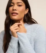 Suéter corto de punto liviano color blanco, con cuello alto y mangas largas.