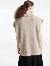 Poncho de punto color azul, con cuello polo y escote en V profundo, sin mangas y diseño holgado.