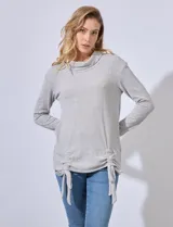 Buzo gris de tejido labrado, con cuello volcado y ruedo con terminaciones fruncidas regulables con lazo.