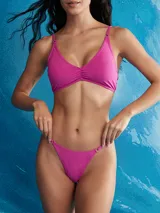 Bikini de dos piezas color blanco, con corpiño de escote en V y frunce central, y tanga de tiro bajo con tiras finas ajustables a los costados.