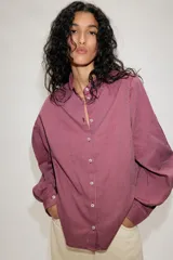 Camisa de manga larga con cuello solapa, cierre frontal con botones y bajo asimétrico, con estampado de rayas verticales.