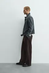Pantalón de hombre color marrón oscuro, de corte balloon fit, con cintura con trabillas y cierre frontal de botón y cremallera. Presenta bolsillos delanteros y bolsillos traseros de vivo.