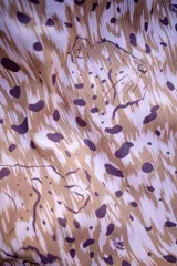 Malla enteriza asimétrica con estampado abstracto en tonos marrones y rosados.