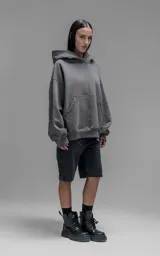 Hoodie oversize de corte crop, color gris oscuro, confeccionado en frisa de algodón. Presenta capucha forrada, bolsillo tipo canguro frontal y puños elásticos.
