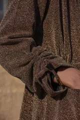 Chaqueta de crepé elastizado de lurex oro viejo, con corte clásico y cierre frontal con botones.