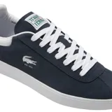 Championes Lacoste modelo Baseshot, de diseño urbano y perfil bajo. Confeccionados en gamuza color azul marino, presentan cordones blancos, suela de goma blanca y el logo del cocodrilo bordado en el lateral con la inscripción EST. 1933.
