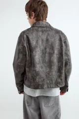 Campera de cuero sintético efecto gamuzado, color negro, con cuello camisero y cierre frontal metálico.