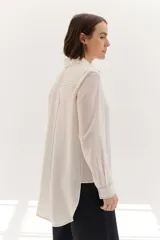 Camisa color crema de lyocell con cuello clásico, cierre frontal con botones, bolsillo de parche en el pecho y pespuntes a contraste en negro.