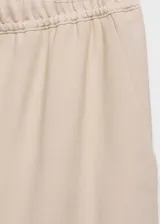 Pantalón fluido de tiro medio, color beige, de corte recto y pernera ancha. Cuenta con cintura elástica con cordón ajustable y bolsillos laterales.