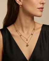 Set compuesto por un collar doble de cadena fina con dijes de esferas doradas y un par de aros tipo caravana con dije de esfera dorada, confeccionados en acero con baño de oro.