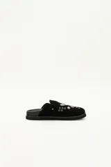 Zueco de cuero descarne negro con diseño de estilo western, decorado con tachas metálicas plateadas y una hebilla lateral ajustable.