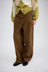 Pantalón de tiro medio confeccionado en tejido de pana, con diseño de pierna ancha, bolsillos delanteros y traseros, y cierre frontal con cremallera y botón.