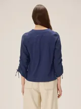 Remera de manga larga color blanco con cuello redondo y detalles fruncidos con lazos en las mangas.