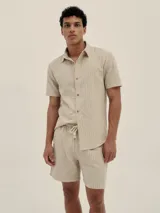 Camisa de manga corta color beige con rayas verticales finas en tonos marrones y blancos.