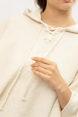 Poncho tejido en telar en 100% lana merino color crudo, con capucha y cordones de ajuste.
