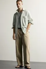Pantalón relaxed fit de color beige, confeccionado en tejido con mezcla de algodón y lino, con diseño de cinco bolsillos, efecto lavado y cierre frontal con cremallera y botón.
