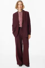 Blazer de corte sastrero en color bordó, con solapas clásicas, cierre frontal de un botón y diseño de hombros estructurados.