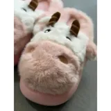 Pantuflas de peluche con diseño de vaca, confeccionadas en piel sintética suave. Cuentan con suela de goma antideslizante y diseño abierto en el talón.