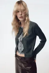 Chaqueta de punto con diseño de doble capa, cuello redondo y manga larga. Presenta una capa exterior gris oscuro y una capa interior gris claro con estampado de rombos, ambas con cierre frontal de botones.
