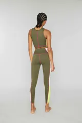 Crop top deportivo verde oliva sin mangas de lycra con banda lateral color block en amarillo y rosa y pespuntes overlock en contraste. Estampado de logotipo en la parte delantera.
