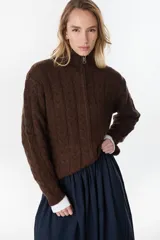 Campera de punto tejido color beige con diseño de ochos, cuello alto y cierre frontal completo.