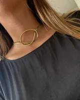 Gargantilla rígida dorada con forma de nudo. Hecha artesanalmente en bronce.