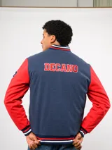 Campera bomber azul marino estilo retro, con cierre frontal de botones a presión, cuello, puños y ruedo con tejido acanalado tricolor. Presenta el logo de Umbro y el escudo del Club Nacional de Football bordados en el pecho, junto con el año 1899 y parches decorativos en las mangas.