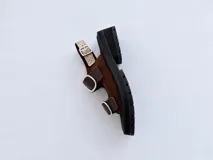 Sandalias de cuero charolado bordó con punta redonda, suela flatform chunky negra con ranuras, y dos tiras frontales con grandes hebillas metálicas plateadas y una tira trasera ajustable.
