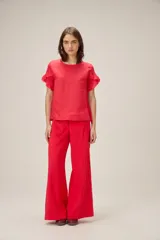 Blusa de lino color rosado, de corte recto y holgado, con cuello redondo y mangas cortas adornadas con volados.
