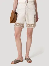 Short tejido a crochet de color beige con detalles geométricos en tono marrón en el borde inferior y lateral. Cuenta con cintura elástica y cordón ajustable con borlas.