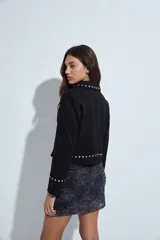 Campera estilo biker de símil gamuza color marrón, con cierre frontal y detalles de tachas metálicas en solapas, mangas y ruedo.