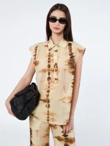 Blusa sin mangas color beige con estampado batik en tonos marrones, cuello camisero, abotonada al frente y corte holgado.