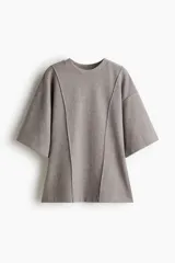 Top de punto fino color gris, con cuello redondo, hombros caídos, mangas al codo y costuras decorativas verticales en el frente que le dan un bajo levemente acampanado.