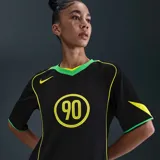 Camiseta Nike Total 90 Energy de color negro, con detalles en amarillo flúor y verde, de manga corta y cuello en V. Presenta un diseño inspirado en los años 2000 con el número 90 impreso en el centro del pecho y ribetes curvados en contraste.