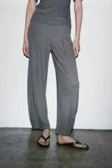 Pantalón de tiro alto con pierna ancha y cintura elástica ajustable. Presenta un diseño de corte holgado con costuras verticales frontales que definen su silueta.