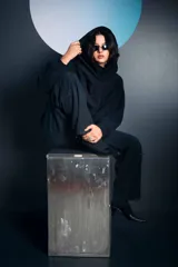 Buzo negro de corte oversize con cuello alto tipo polera y capucha integrada. Presenta mangas largas con puños ajustados y un diseño holgado en el cuerpo.