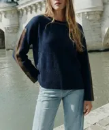 Sweater de tejido de punto con calce oversize, color azul marino con detalles en color marrón en las mangas y cuello. Presenta un diseño de manga larga y puños y ruedo acanalados.