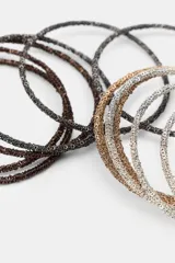 Pack de pulseras rígidas de estilo minimalista, compuestas por múltiples aros de textura rugosa en tonos plateado, dorado y bronce.