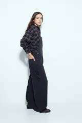 Enterito de denim negro con calce relajado y silueta amplia, inspirado en la estética workwear. Presenta tiradores regulables, pechera con bolsillo frontal y bolsillos laterales funcionales.