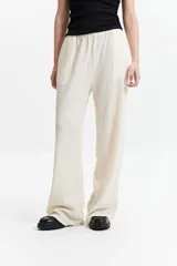 Pantalón de vestir de tiro alto, color crema, con textura crepe arrugada y pierna ancha y fluida. Presenta cintura elástica.