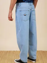 Jean de corte baggy fit en denim color azul claro, con diseño de cinco bolsillos y cierre frontal con botón metálico.
