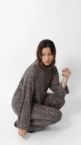 Conjunto de dos piezas compuesto por un sweater de cuello redondo y mangas largas holgadas, y un pantalón de corte recto, ambos confeccionados en tejido acanalado con estampado animal print de leopardo en tonos marrones y grises.