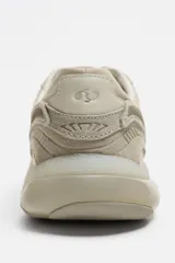 Zapatilla deportiva tipo running de color negro, perteneciente a la colección especial Origins. Presenta una parte superior confeccionada en una combinación de cuero con acabado de gamuza y tejido transpirable. Cuenta con una suela de volumen con diseño irregular y cierre mediante cordones.