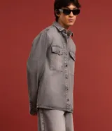 Camisa masculina de denim de algodón con efecto marmolado, corte oversized tipo boxy, cuello camisero, mangas largas, cierre frontal con botones y dos bolsillos frontales con solapa en el pecho.