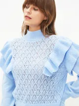 Buzo de tejido de punto calado en color lila, con cuello alto, mangas largas con puños ajustados y detalle de volados en los hombros.