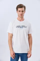 Remera azul marino de manga corta con cuello redondo, confeccionada en mezcla de algodón y poliéster. Presenta un diseño en el frente que combina estampa y bordado con la leyenda "Legacy Brand 1972" en tonos rosado, verde y marrón.
