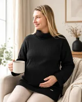 Polerón negro de punto con cuello alto, manga larga y diseño de textura acanalada. Presenta un corte holgado y una pequeña placa metálica decorativa en el ruedo.