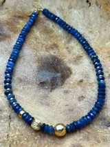 Collar corto de cuentas facetadas color azul con detalles de cuentas doradas.